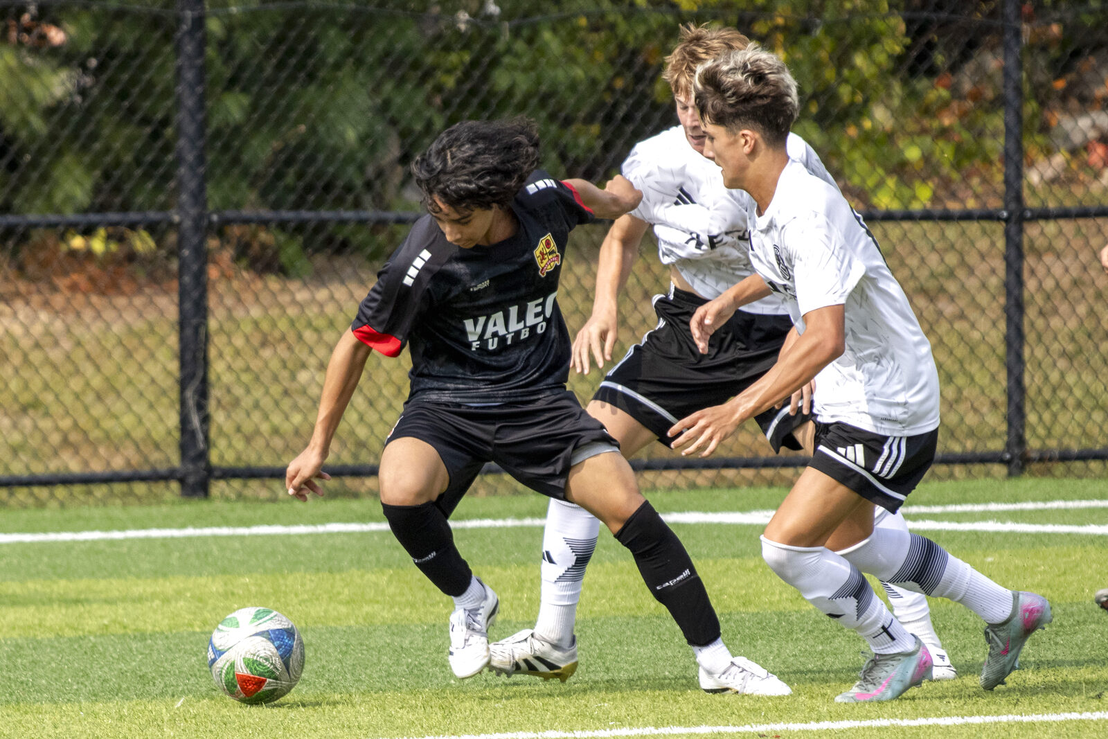 Valeo FC player dribbling past two defenders