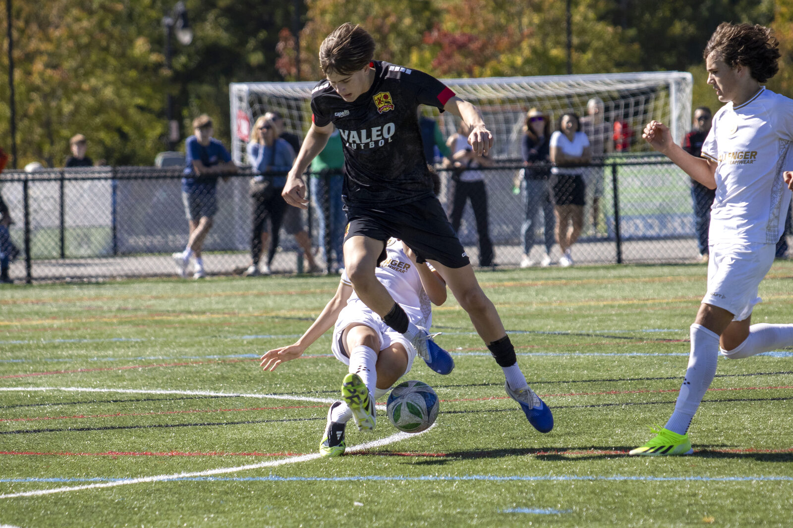Valeo FC player leaping over a sliding defender